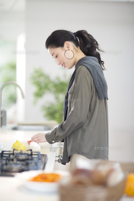 キッチンで料理の準備をする女性の横顔 の写真素材 イラスト素材 アマナイメージズ