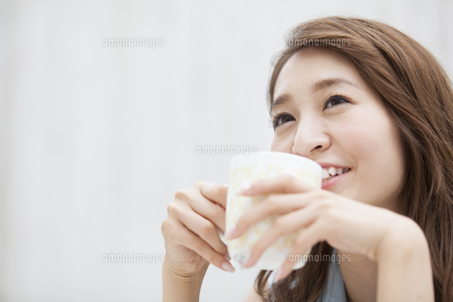 微笑みながら両手でカップを持つ女性 の写真素材 イラスト素材 アマナイメージズ