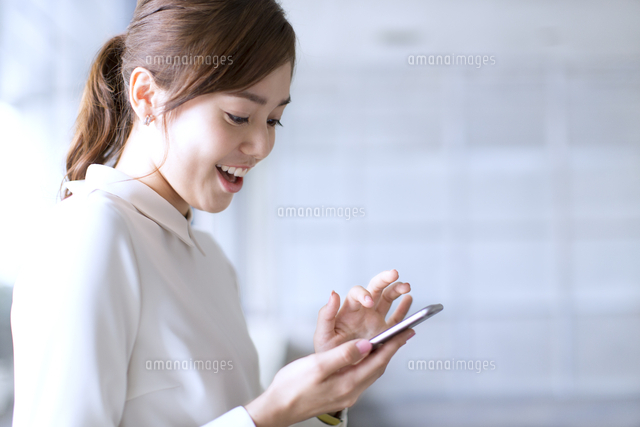 スマートフォンを見て笑うビジネス女性 の写真素材 イラスト素材 アマナイメージズ