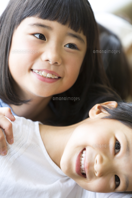 重なって笑う小学生の女の子2人 の写真素材 イラスト素材 アマナイメージズ