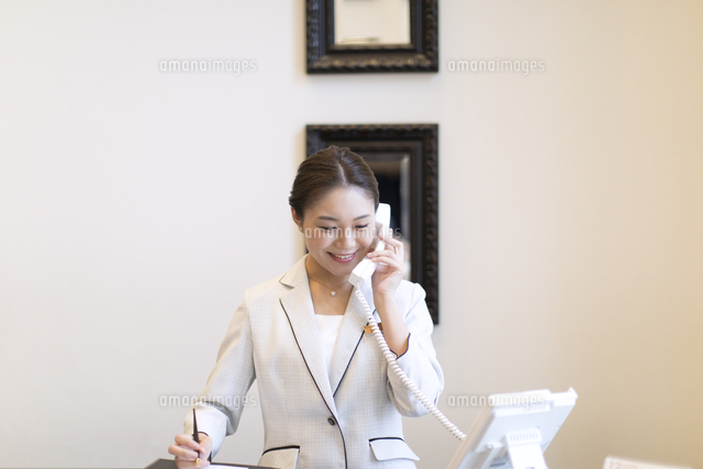 電話対応をするコンシェルジュの女性 の写真素材 イラスト素材 アマナイメージズ