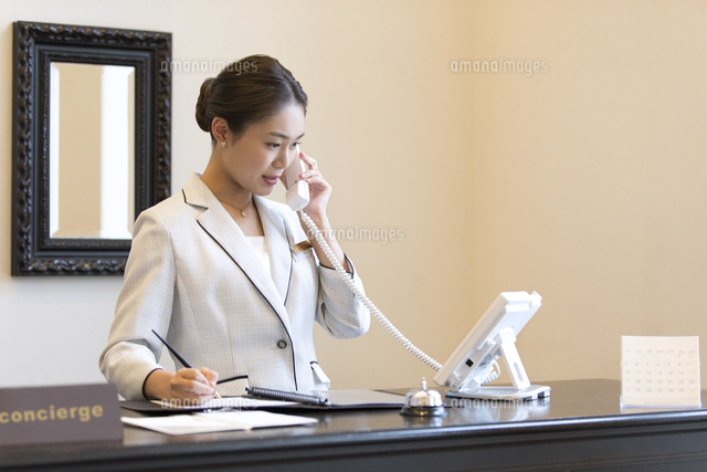 電話対応をするコンシェルジュの女性 の写真素材 イラスト素材 アマナイメージズ