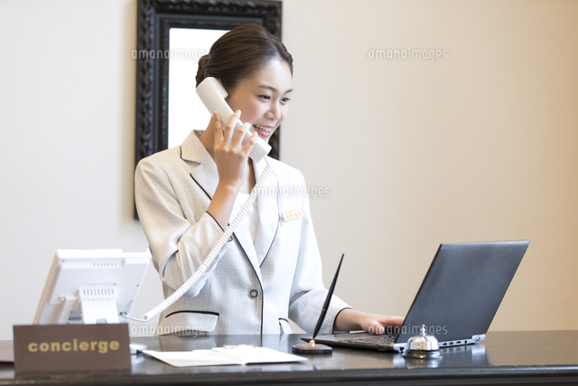 電話対応をするコンシェルジュの女性 の写真素材 イラスト素材 アマナイメージズ