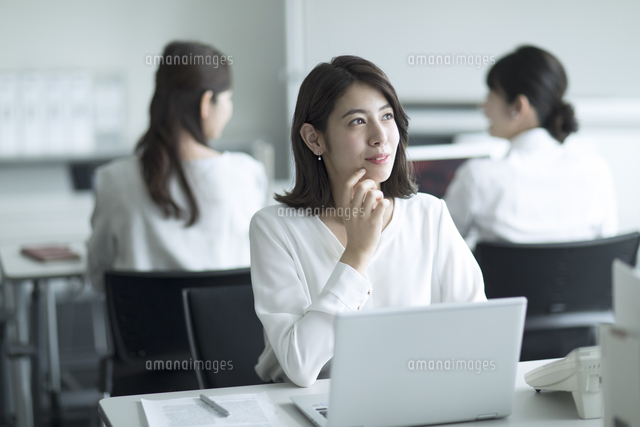 パソコンの前で遠くを見るビジネス女性 の写真素材 イラスト素材 アマナイメージズ