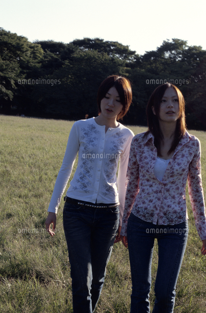 野原を並んで歩く2人の日本人女性 の写真素材 イラスト素材 アマナイメージズ