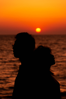 沈む夕日とカップルのシルエット[10112002934]の写真・イラスト素材
