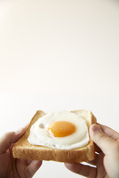 目玉焼きが乗ったトーストを持つ手 の写真素材 イラスト素材 アマナイメージズ