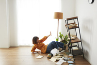 地震で倒れてきた本棚の横で驚く女性 の写真素材 イラスト素材 アマナイメージズ