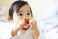 おもちゃを口に入れている赤ちゃん[10568008772]の写真・イラスト素材