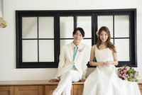 窓際に座る幸せな代新郎新婦 の写真素材 イラスト素材 アマナイメージズ