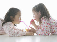 向かい合いストローでジュースを飲む女の子 の写真素材 イラスト素材 アマナイメージズ