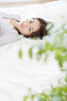 ベッドに横たわる日本人女性[30018001274]の写真・イラスト素材